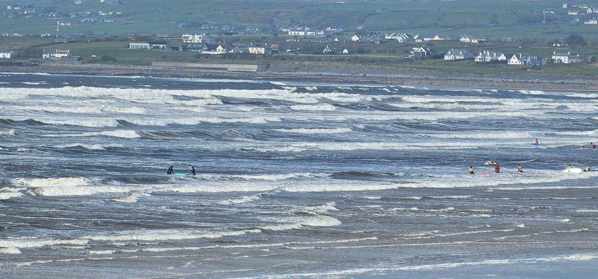 a few beginner surfers in the white water at the north end of the beach 